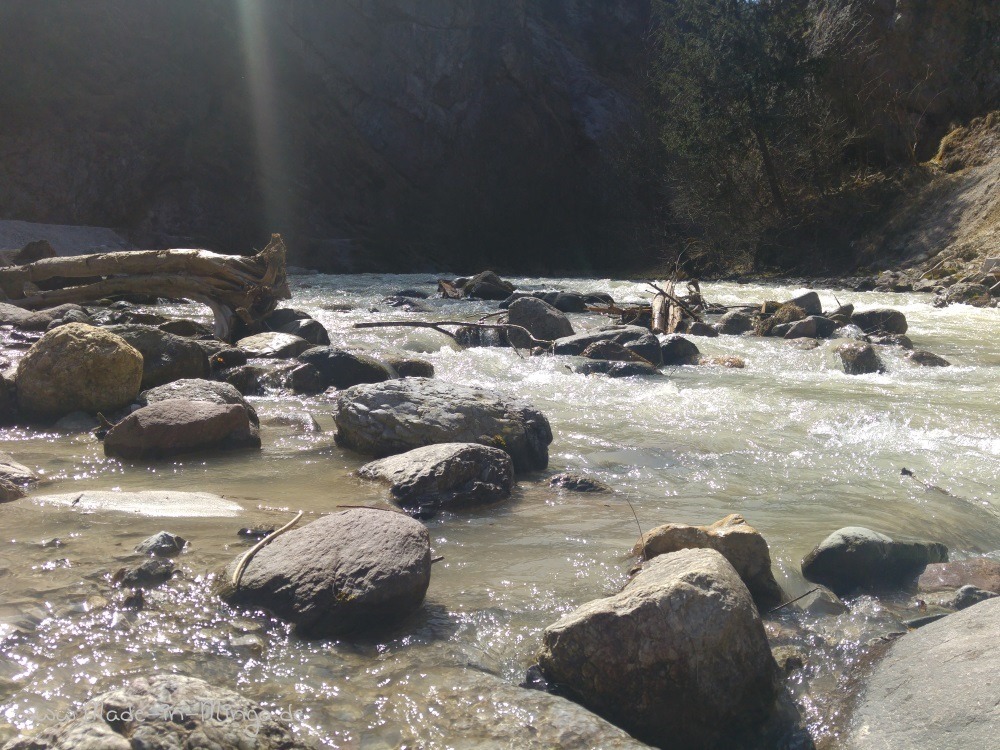 Mit den Füßen im Wasser der Ache sitzen