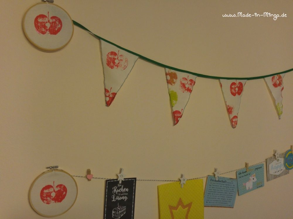 Wimpelkette und Apfel im Stickrahmen zusammen an der Wand dekorieren
